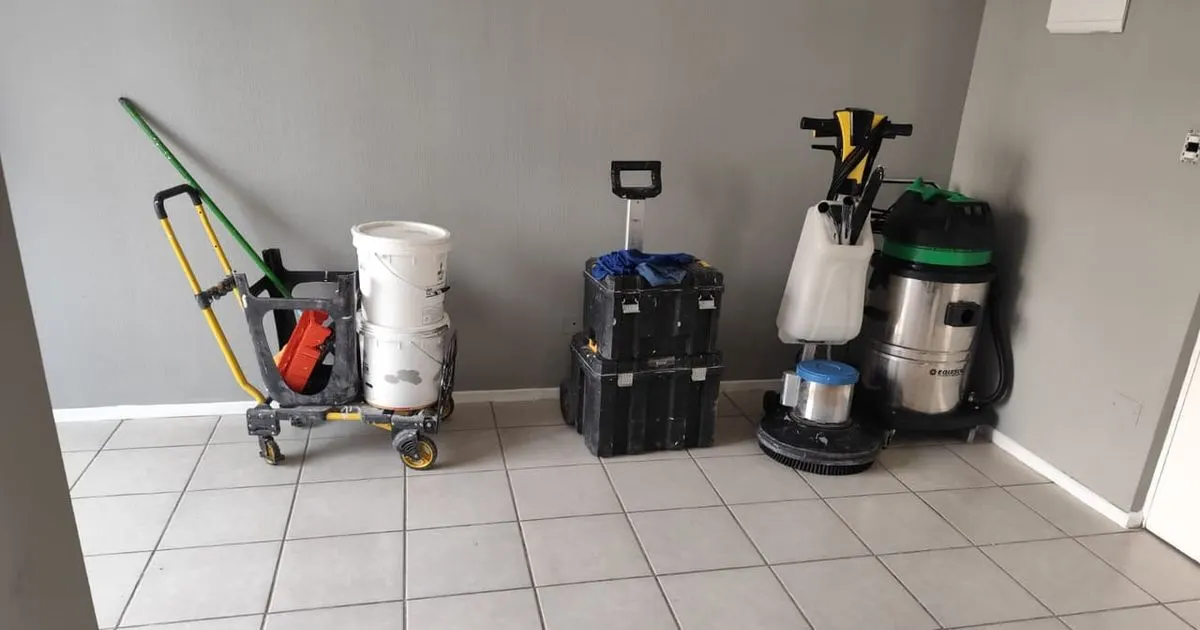 Nuestros equipos de lavado ordenados contra un muro: un carro con baldes, cajas de herramientas, una máquina rotativa con escobilla y una aspiradora de agua
